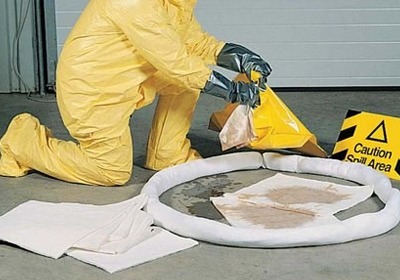 Workers cleaning a chemical spill in a UK industrial workplace using spill control equipment